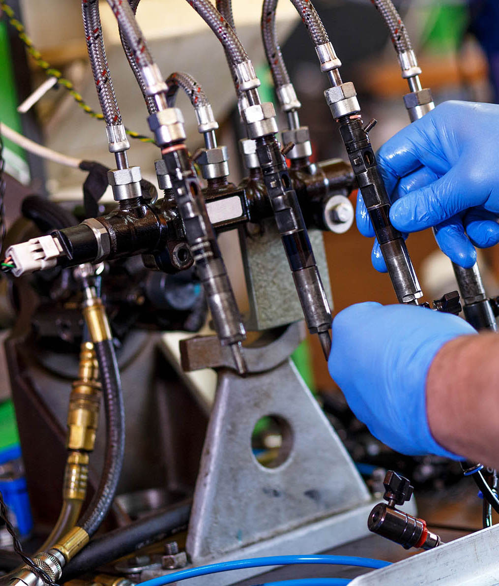Professional mechanic testing diesel injector in his workshop.